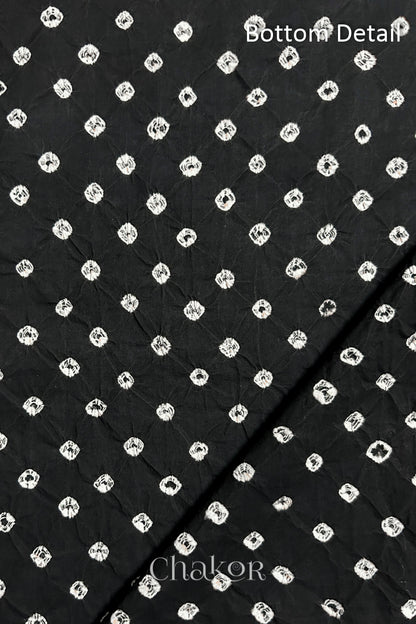Close up of bottom fabric in  black patterned with bandhani tie dye dots, folded at the corner displaying texture and detail. Text reads bottom.
