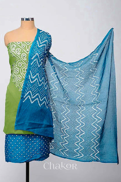 A stylish kurta set fabric featuring a mehendi green mirror embroidered top, a bandhani turquoise blue bottom, and a matching turquoise blue dupatta draped elegantly. Text reads Chakor.
