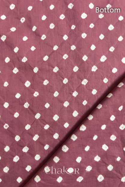 Close up of Bottom fabric in soft rose pink patterned with bandhani tie dye dots, folded at the corner displaying texture and detail.