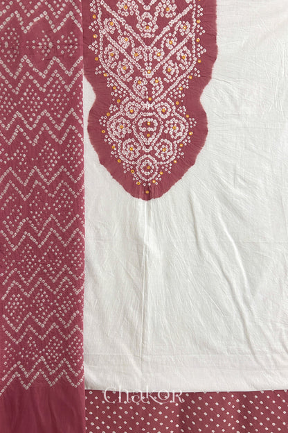 A soft rose pink- white kurta set fabric with intricate bandhani & mirror embroidery, paired with a soft rose pink bottom & odhani featuring a zigzag design.
