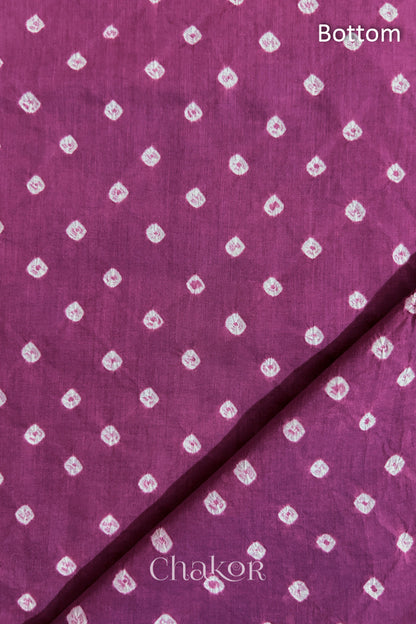 Close up of Bottom fabric in deep violet patterned with bandhani tie dye dots, folded at the corner displaying texture and detail.