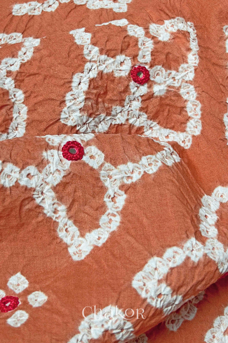 Close-up of Bandhani floral pattern accented with hand embroideBrick Orange mirror work.
