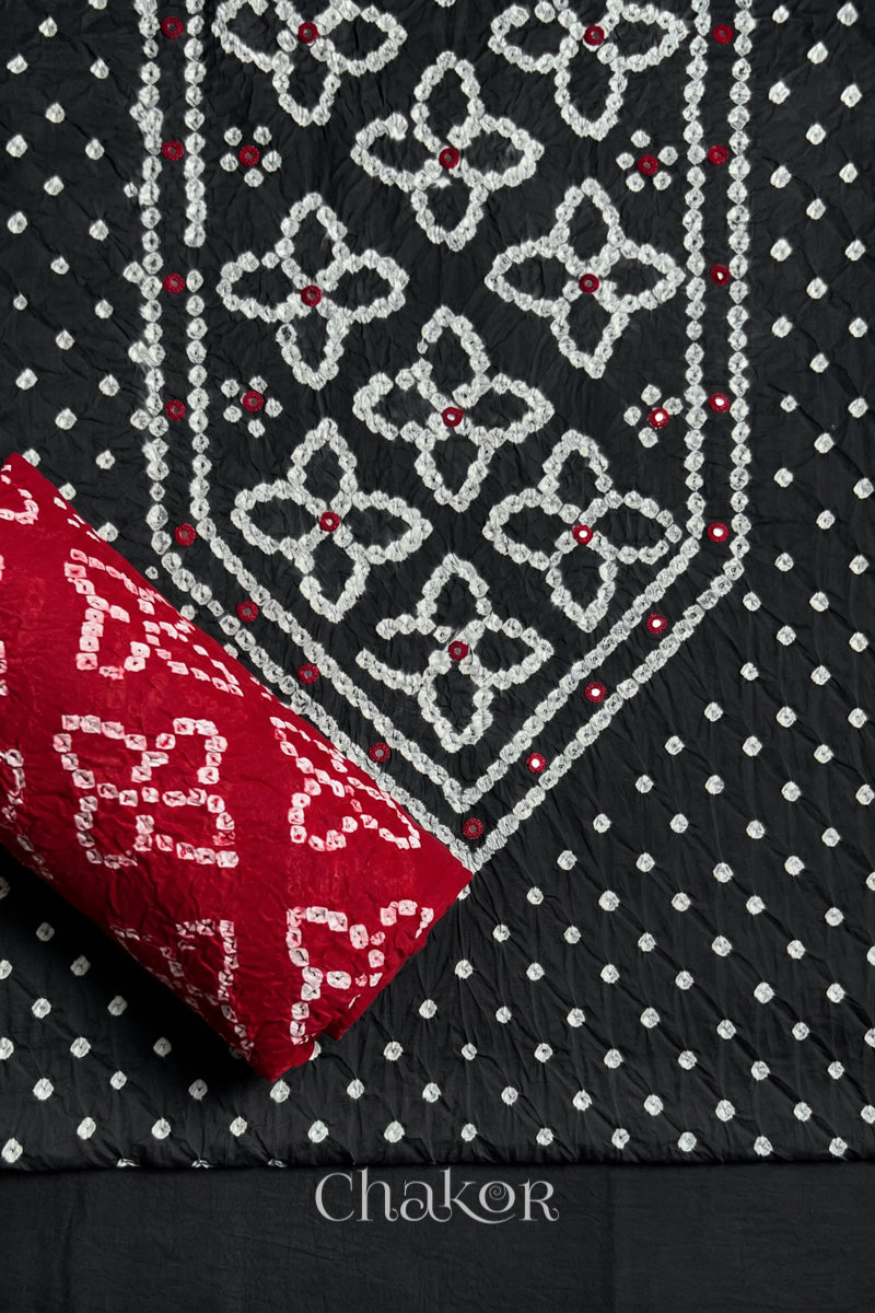 Front yoke detail of Black Bandhani cotton kurta fabric with hand embroidery and mirror work and Red dupatta rolled up.
