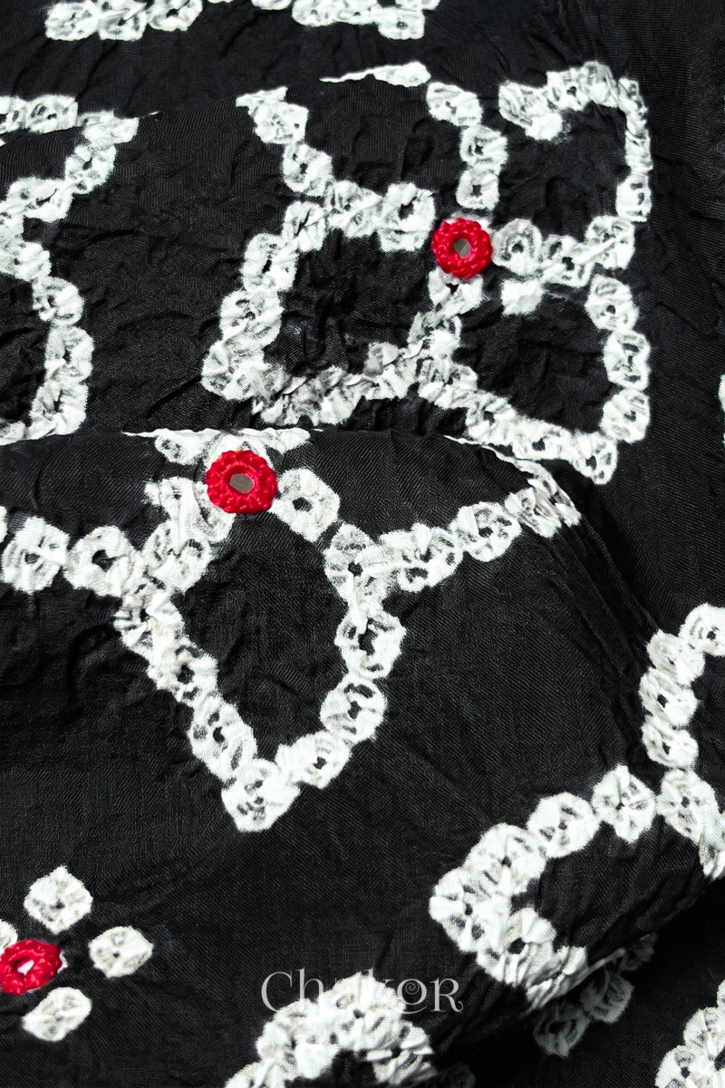 Close-up of Bandhani floral pattern accented with hand embroidery Black mirror work.
