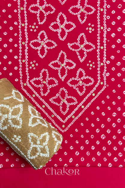 Front yoke detail of Strawberry Pink Bandhani cotton kurta fabric with hand embroidery and mirror work and Beige dupatta rolled up.
