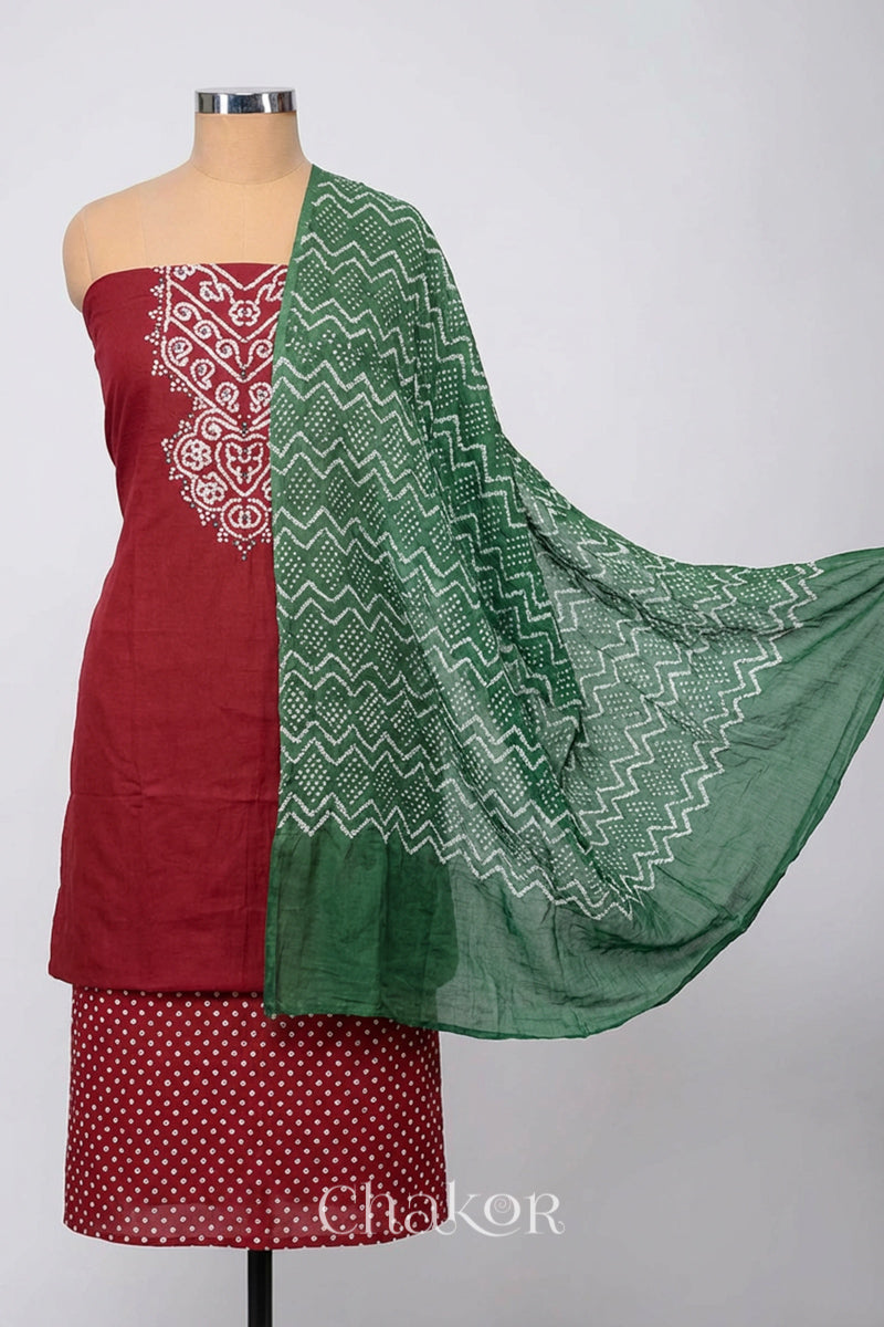A stylish brick red bandhani kurta set fabric featuring mirror embroidered yoke, bandhani bottom and contrast moss green dupatta draped on a dressform.