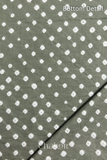 Close up of bottom fabric in cement grey patterned with bandhani tie dye dots, folded at the corner displaying texture and detail. Text reads bottom.
