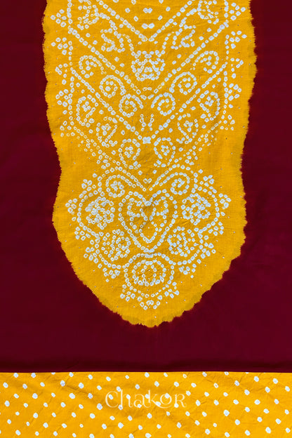 Close-up of red kurta fabric featuring intricate bandhani & yellow mukaish embroidered yoke with bandhani dotted bottom fabric, with Chakor brand watermark.
