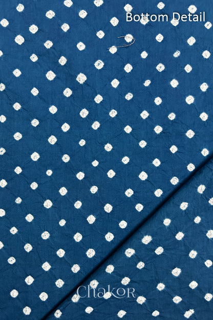Close up of bottom fabric in indigo blue patterned with bandhani tie dye dots, folded at the corner displaying texture and detail. Text reads bottom.
