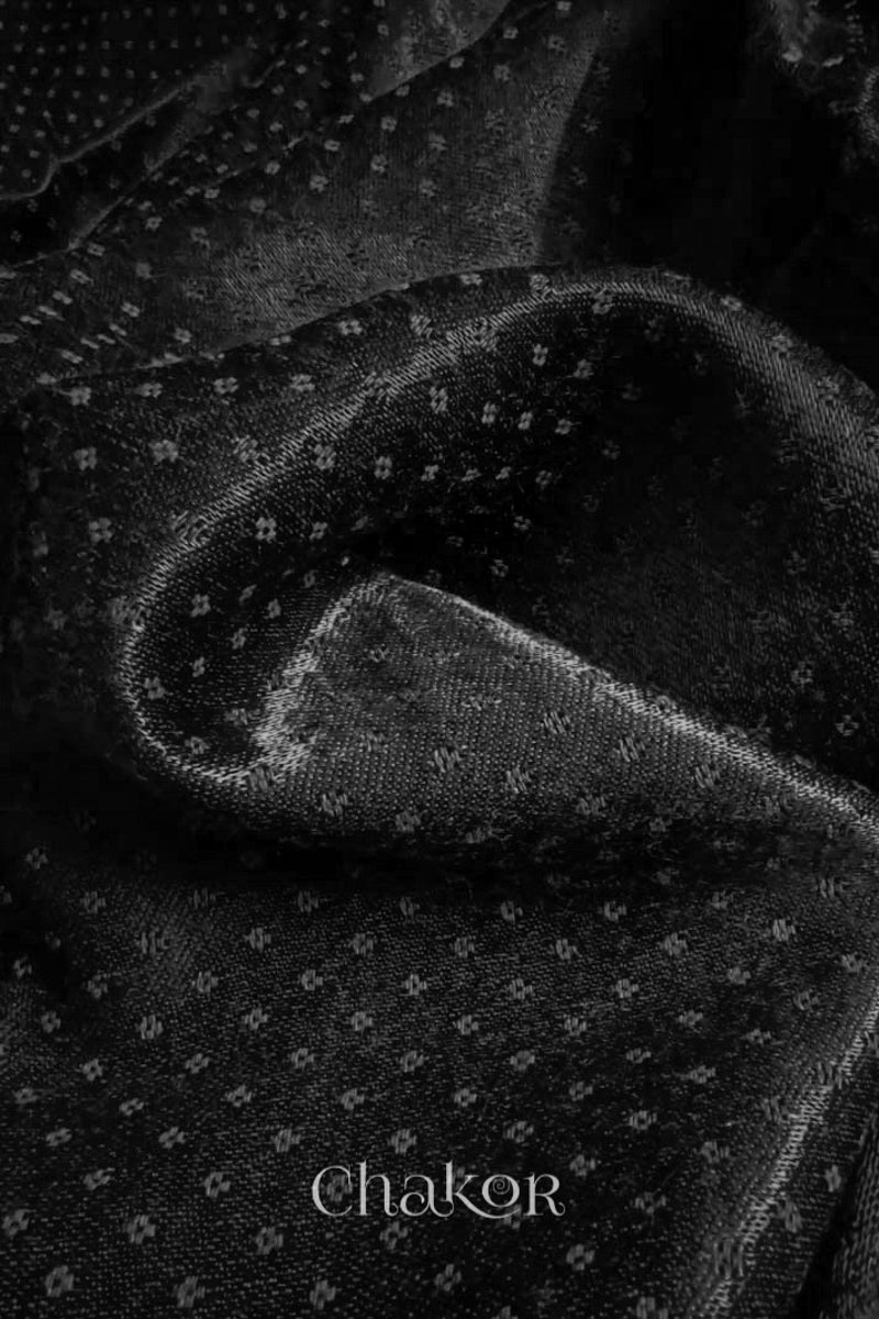 Close-up of black mashru self textured fabric with 'Chakor' logo visible.