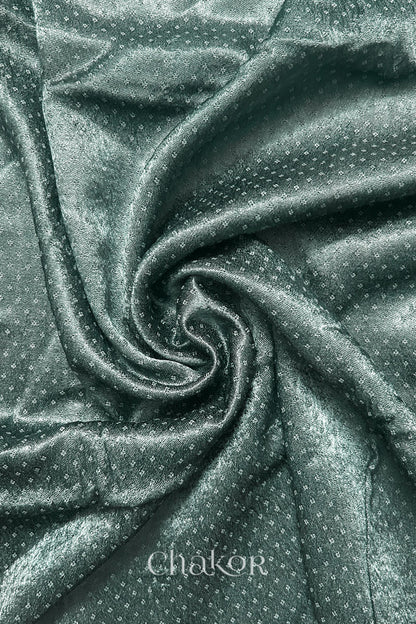 Close-up of Charcoal grey mashru self textured fabric arranged in a swirling design with 'Chakor' logo visible.