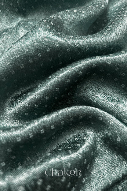 Close-up of Charcoal grey mashru self textured fabric with 'Chakor' logo visible.
