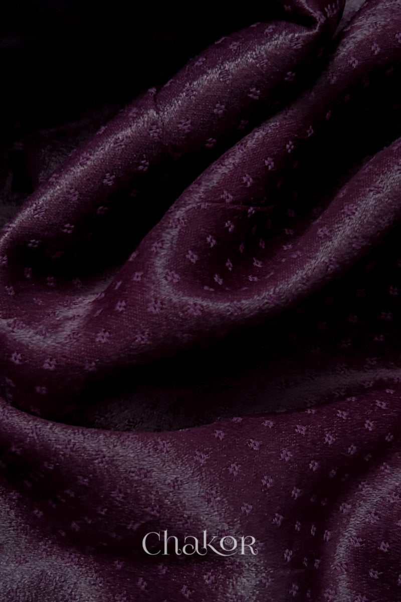 Close-up of dark burgundy mashru self textured fabric with 'Chakor' logo visible.