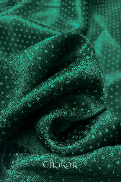 Close-up of dark green mashru self textured fabric with 'Chakor' logo visible.
