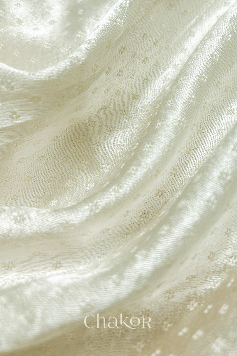 Close-up of off-white mashru self textured fabric with 'Chakor' logo visible.