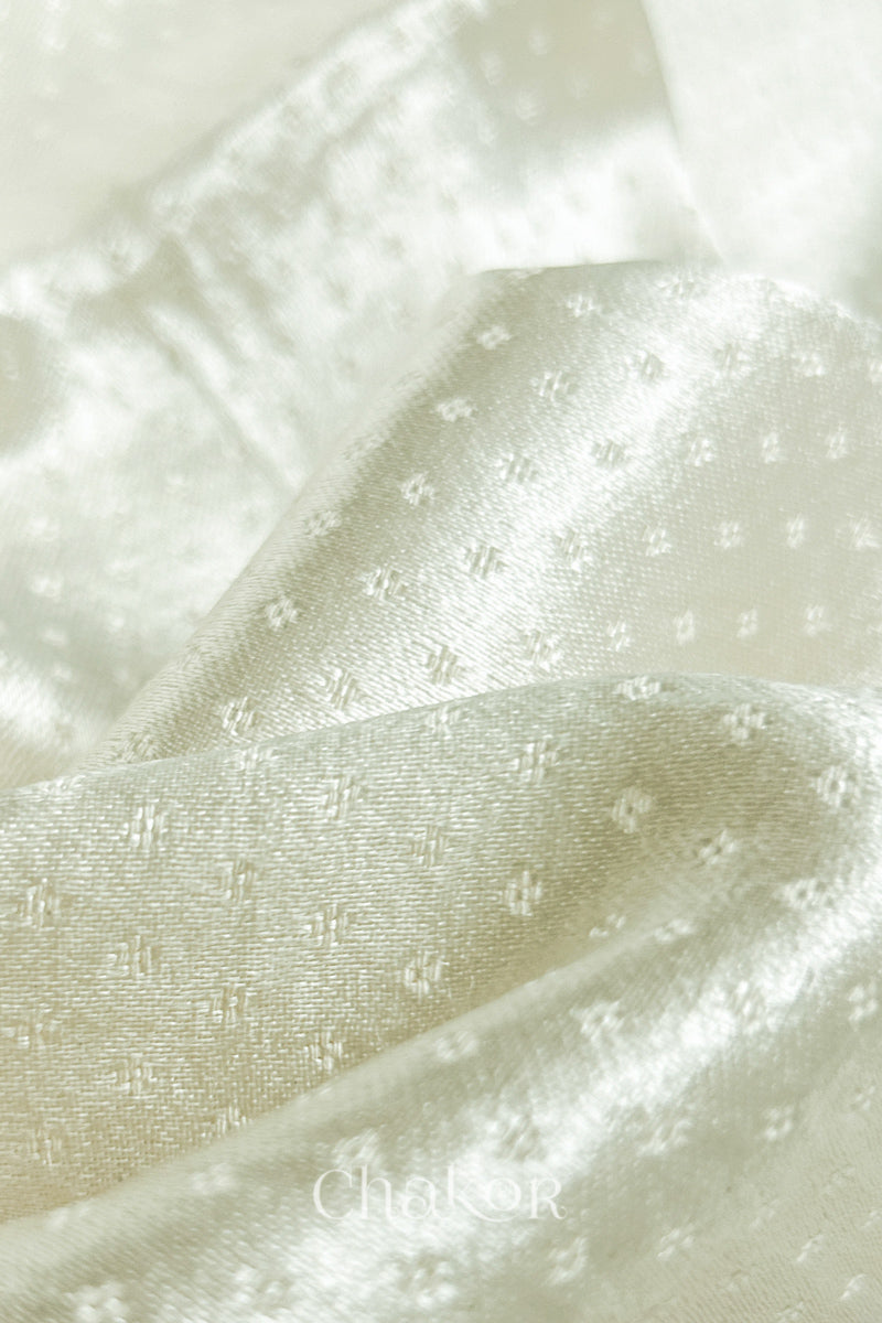 Close-up of off-white mashru self textured fabric with 'Chakor' logo visible.