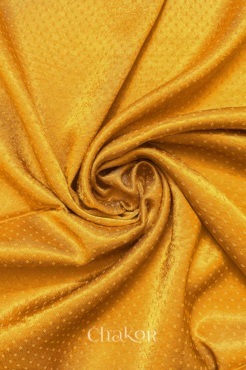 Golden yellow Mashru blouse fabric with silky texture, fabric swirl close-up.
