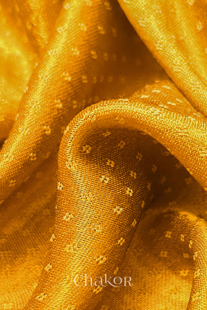 Golden yellow Mashru fabric showing self-textured weave detail.