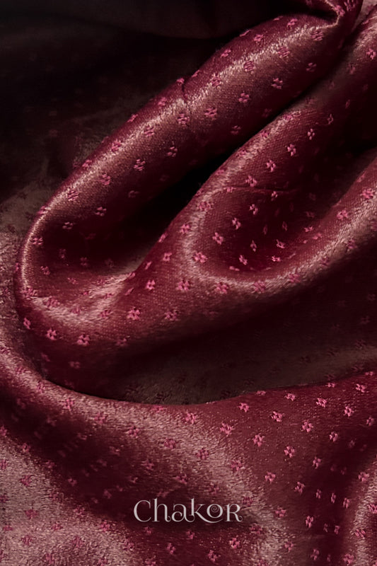 Close-up of maroon mashru self textured fabric with 'Chakor' logo visible.
