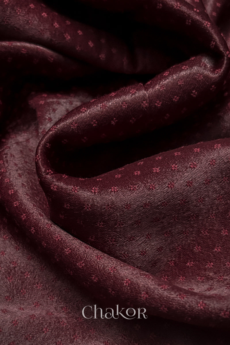 Close-up of maroon mashru self textured fabric with 'Chakor' logo visible.