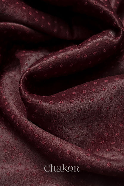 Close-up of maroon mashru self textured fabric with 'Chakor' logo visible.