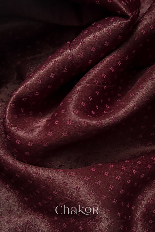 Close-up of maroon mashru self textured fabric with 'Chakor' logo visible.
