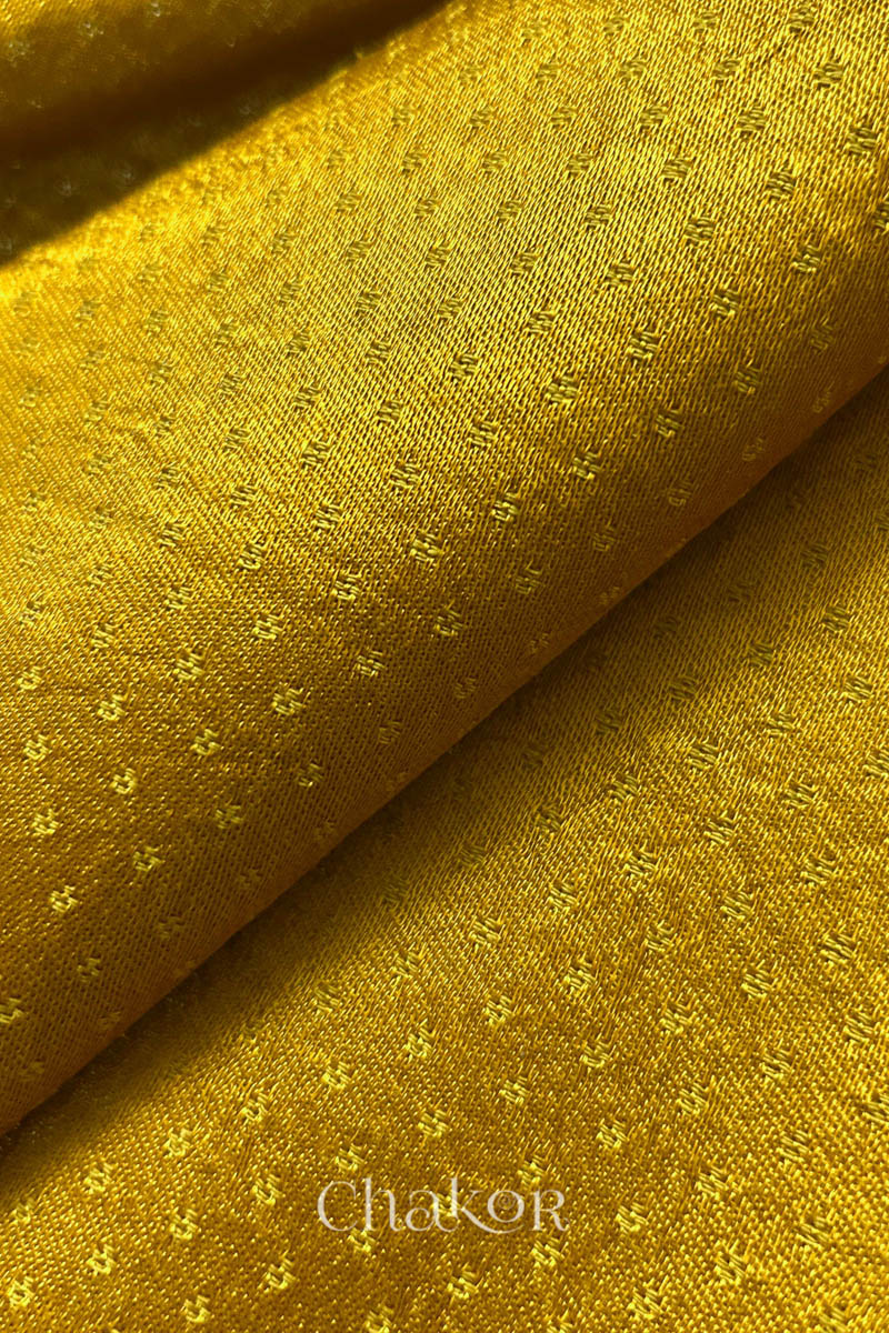 Close-up of mustard yellow fabric with subtle pattern, brand 'Chakor' visible.