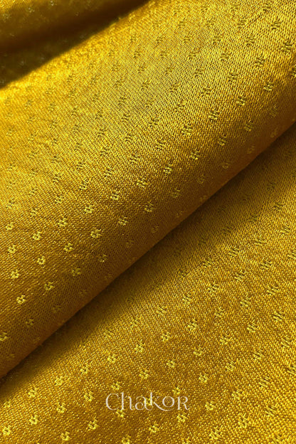 Close-up of mustard yellow fabric with subtle pattern, brand 'Chakor' visible.
