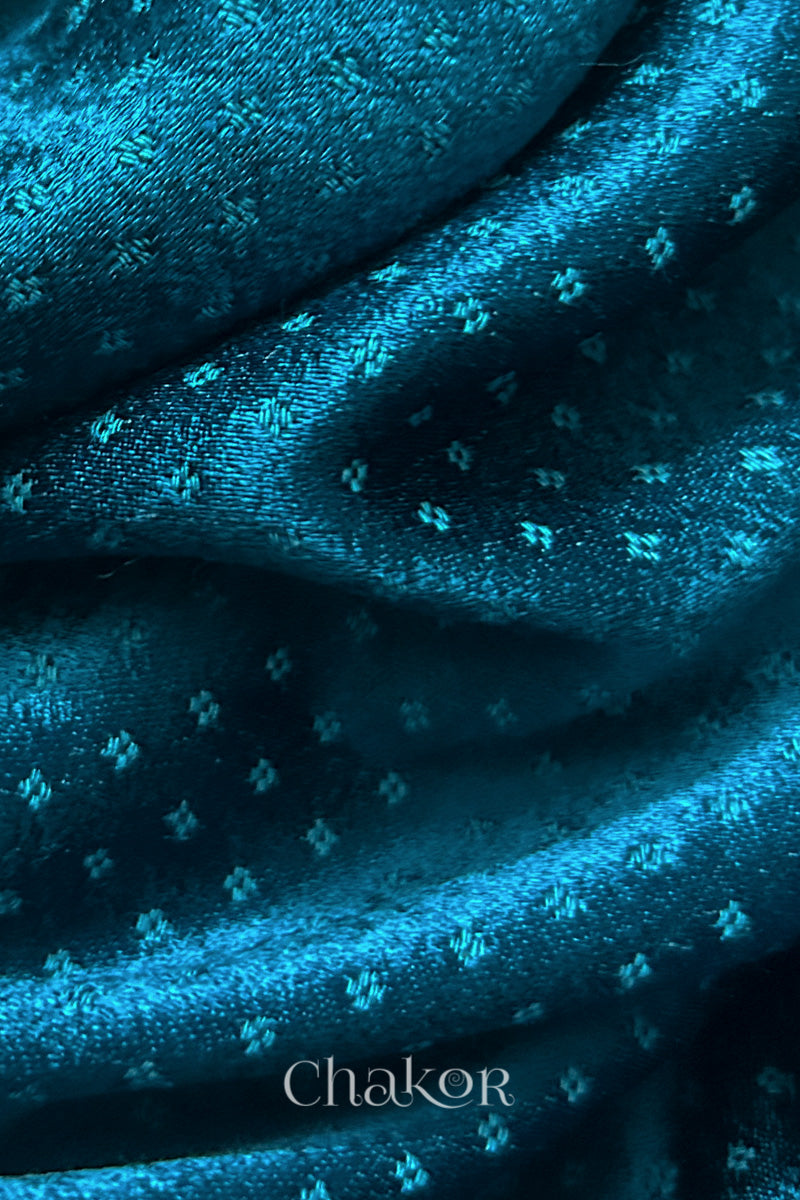 Close-up of deep indigo mashru self textured fabric with 'Chakor' logo visible.