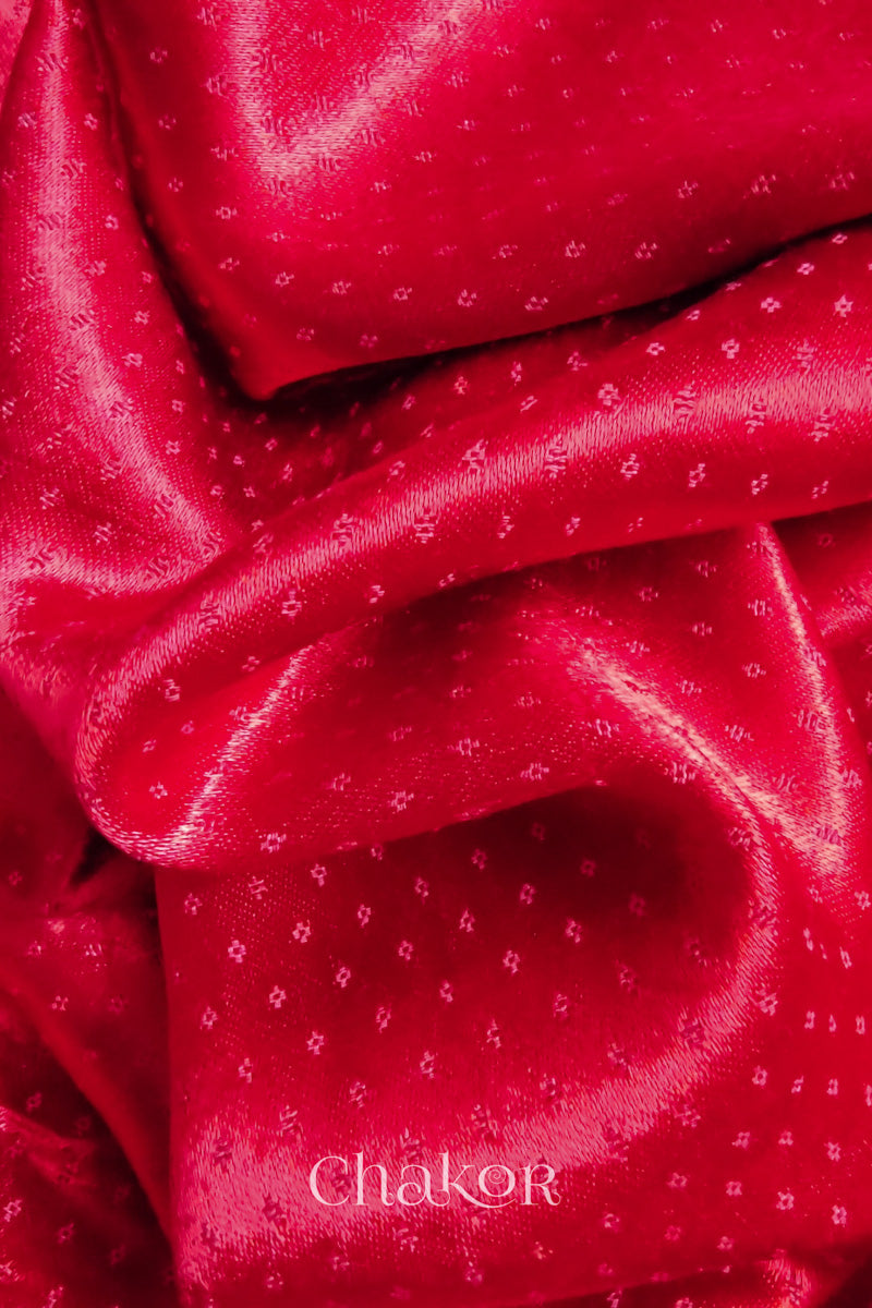 Close-up of red mashru self textured fabric with 'Chakor' logo visible.