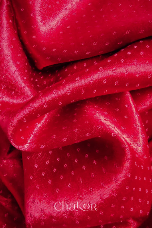 Close-up of red mashru self textured fabric with 'Chakor' logo visible.