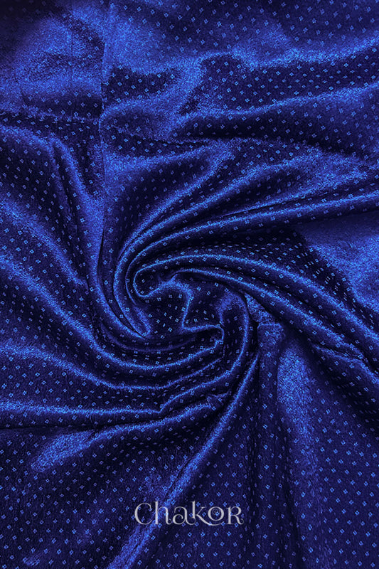 Close-up of royal blue mashru self textured fabric arranged in a swirling design with 'Chakor' logo visible.