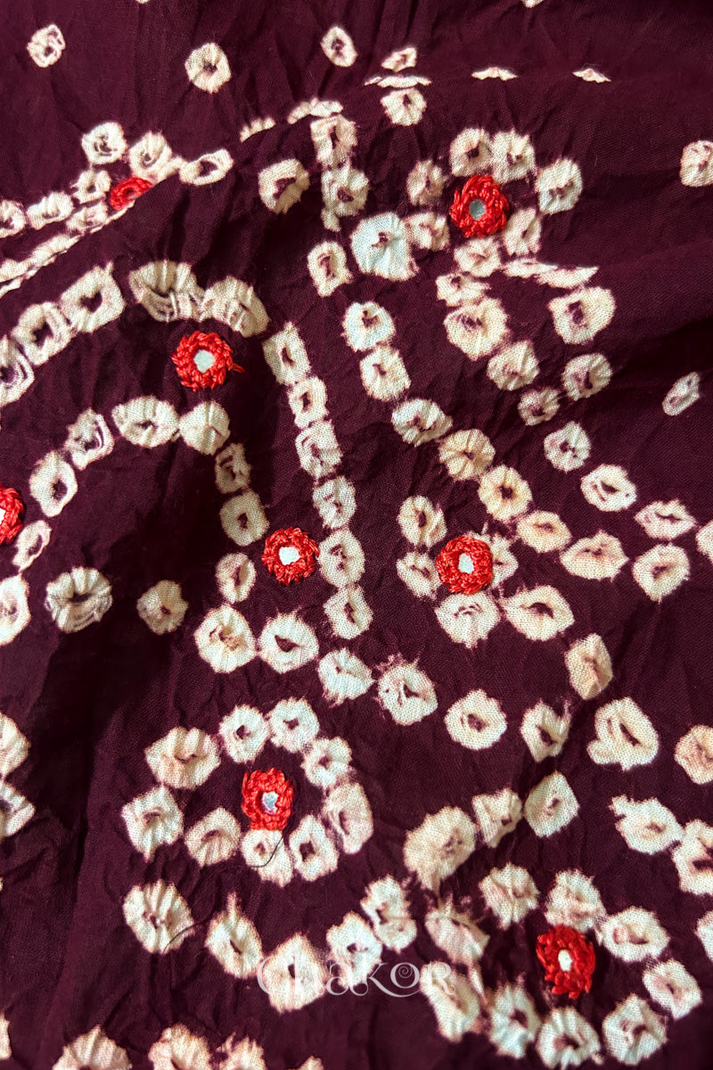 Close-up of Popat Bandhani motifs and hand-embroidered mirror work on Maroon blouse fabric.
