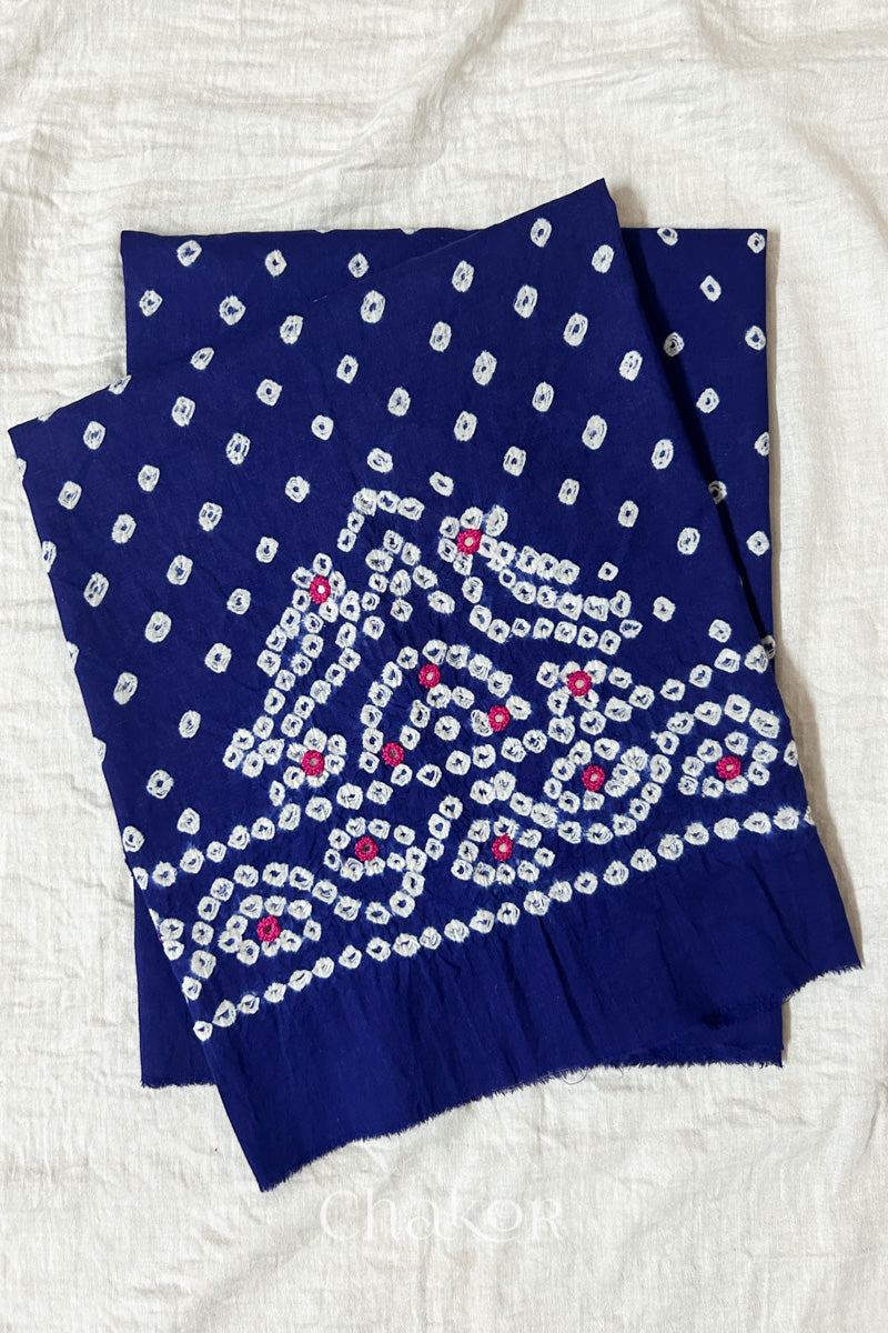 Navy blue Kutch Bandhani cambric cotton unstitched blouse piece folded on white fabric.
