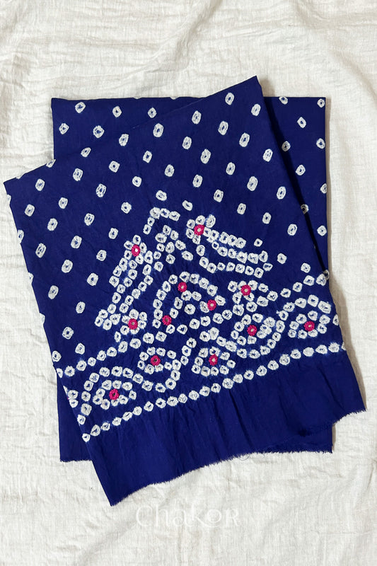 Navy blue Kutch Bandhani cambric cotton unstitched blouse piece folded on white fabric.
