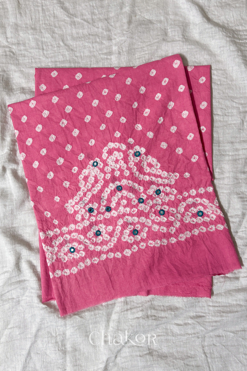 Pink Kutch Bandhani cambric cotton unstitched blouse piece folded on white fabric.
