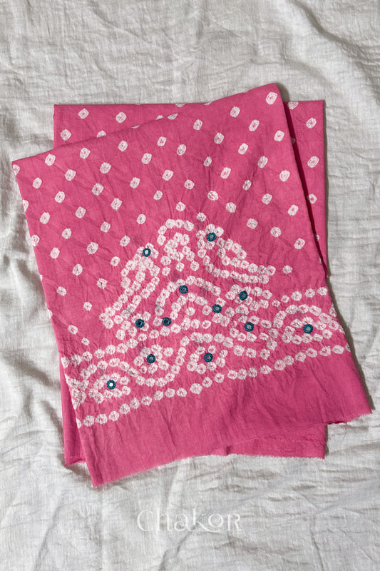 Pink Kutch Bandhani cambric cotton unstitched blouse piece folded on white fabric.
