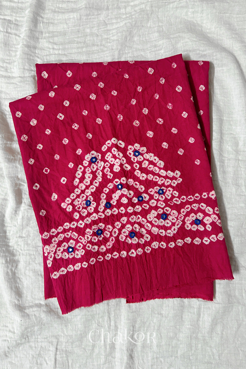 Strawberry pink Kutch Bandhani cambric cotton unstitched blouse piece folded on white fabric.
