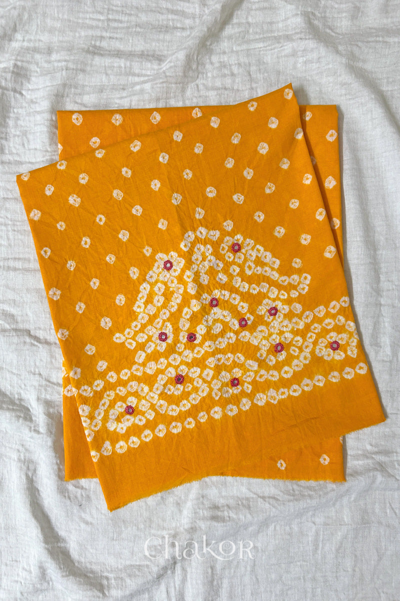 Yellow Kutch Bandhani cambric cotton unstitched blouse piece folded on white fabric.
