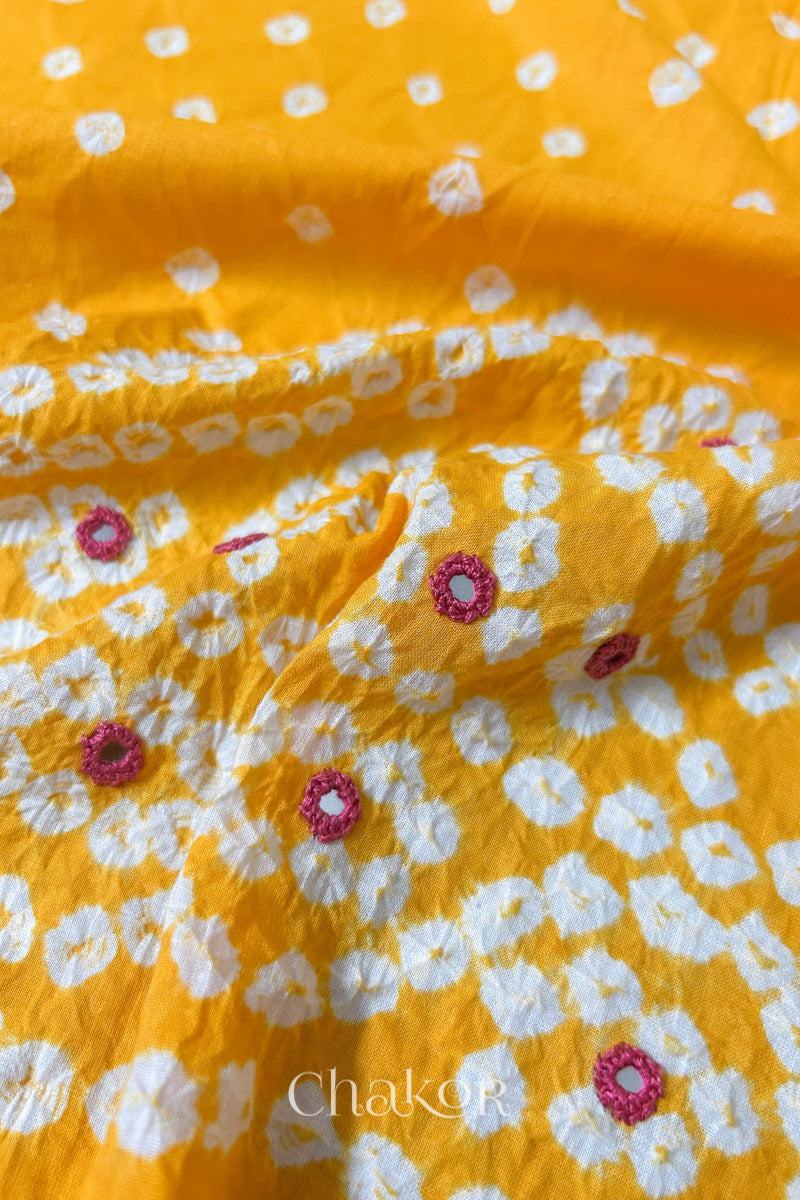 Close-up of Popat Bandhani motifs and hand-embroidered mirror work on Yellow blouse fabric.
