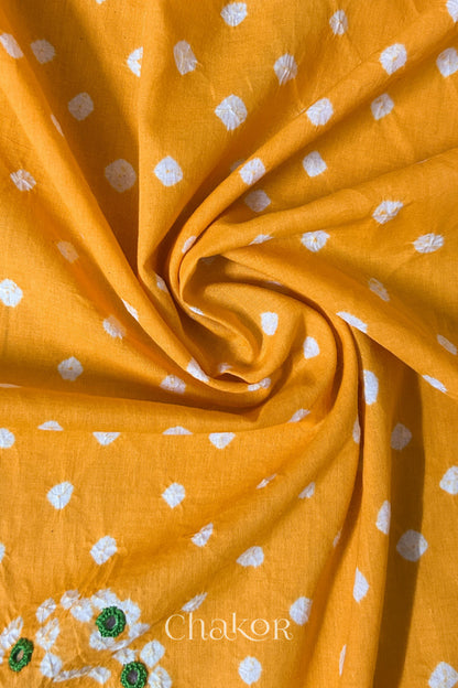 Yellow Bandhani cotton blouse fabric showing fine tie-dye dots and its soft drape.
