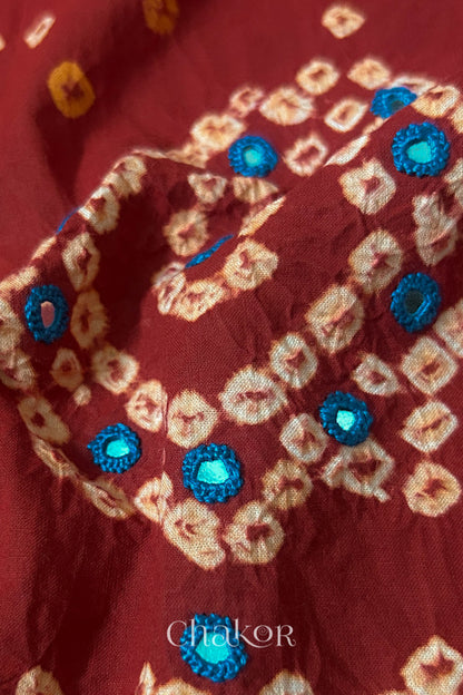 Detail of Kutch Bandhani Keri pattern with mirror embroidery on Red cotton blouse fabric.
