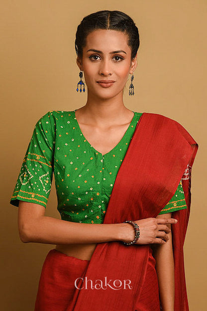 Woman wearing a handcrafted green bandhani blouse in traditional patterns with mirror embroidery.
