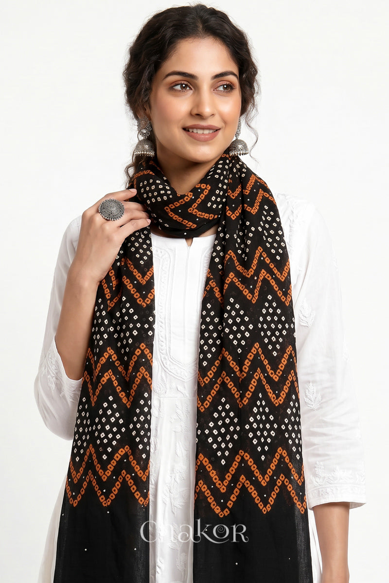 Black Kutch Bandhani mulmul dupatta wrapped around woman's neck.
