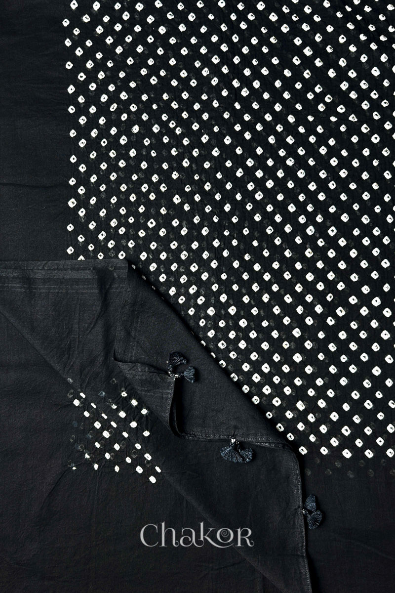 Chakor's black cotton dupatta adorned with white bandhej patterns, featuring decorative tassels at the edges, showcasing intricate craftsmanship.