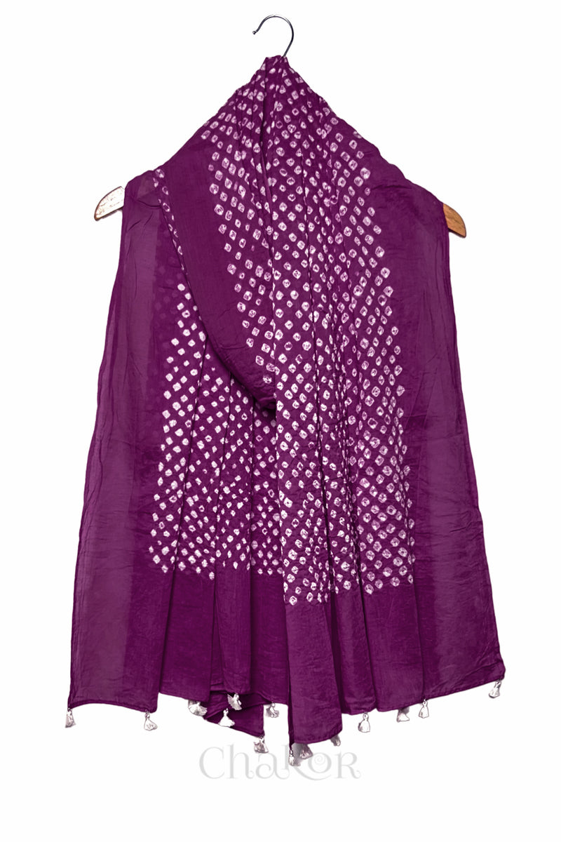 Chakor's magenta cotton dupatta adorned with white bandhani dots, draped elegantly on a wooden hanger, featuring tassels at the edge.