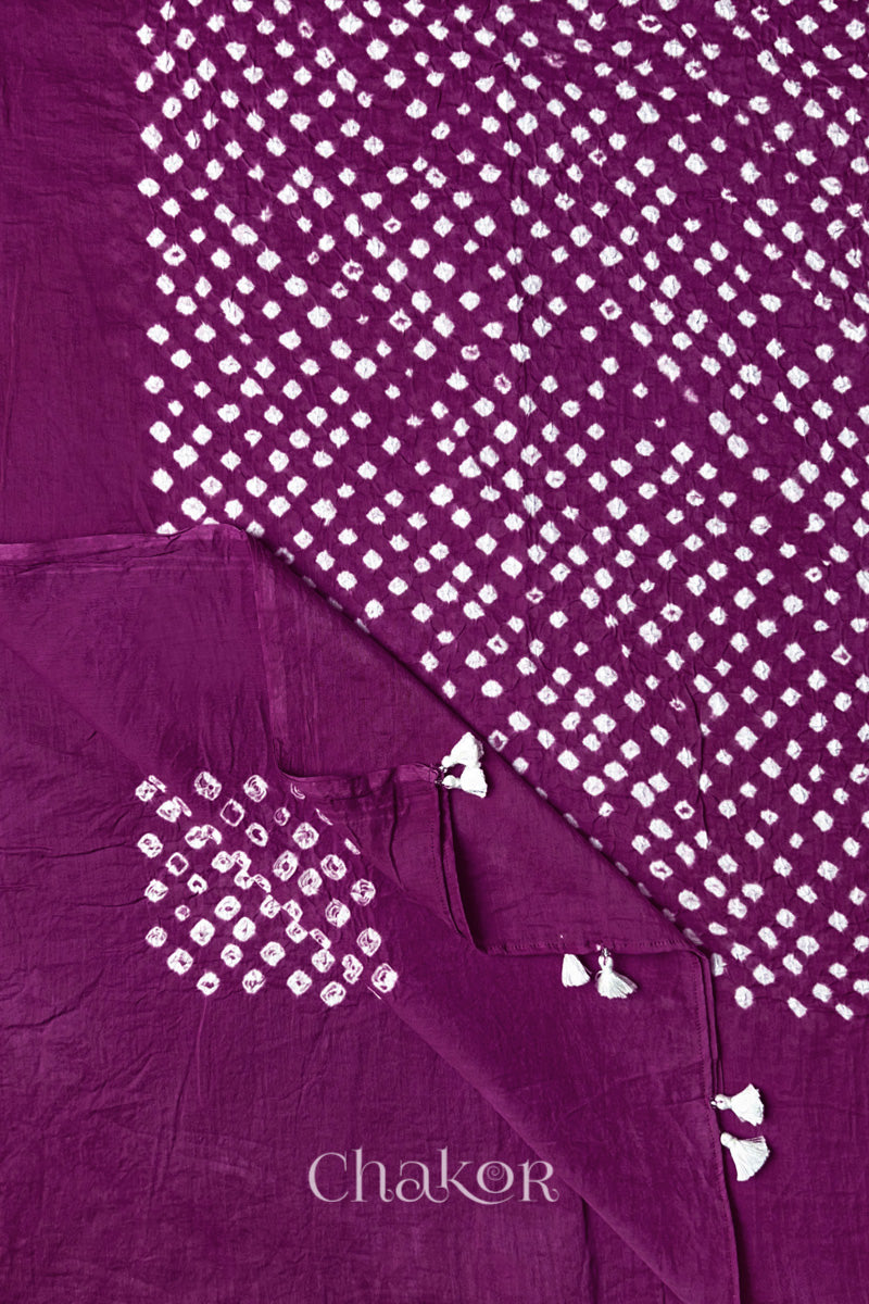 Chakor's magenta cotton dupatta adorned with white bandhej patterns, featuring decorative tassels at the edges, showcasing intricate craftsmanship.
