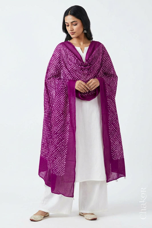 Model wearing magenta Bandhani mul cotton dupatta with tie-dye dot pattern draped over a white kurta.