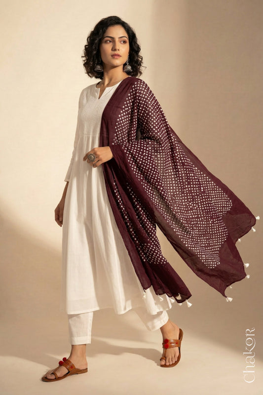 Model wearing Dark maroon Bandhani mul cotton dupatta with tie-dye dot pattern draped over a white kurta.

