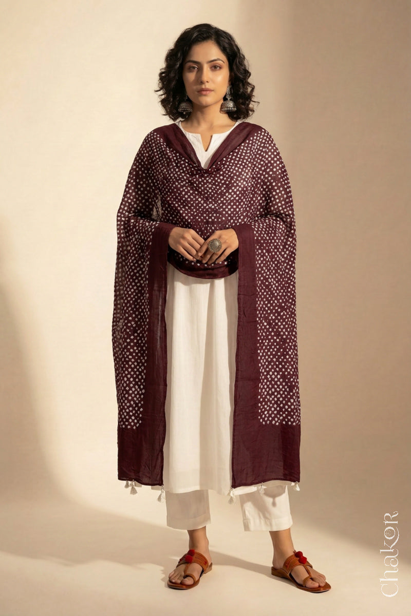 Model wearing Dark maroon Bandhani mul cotton dupatta with tie-dye dot pattern draped over a white kurta.

